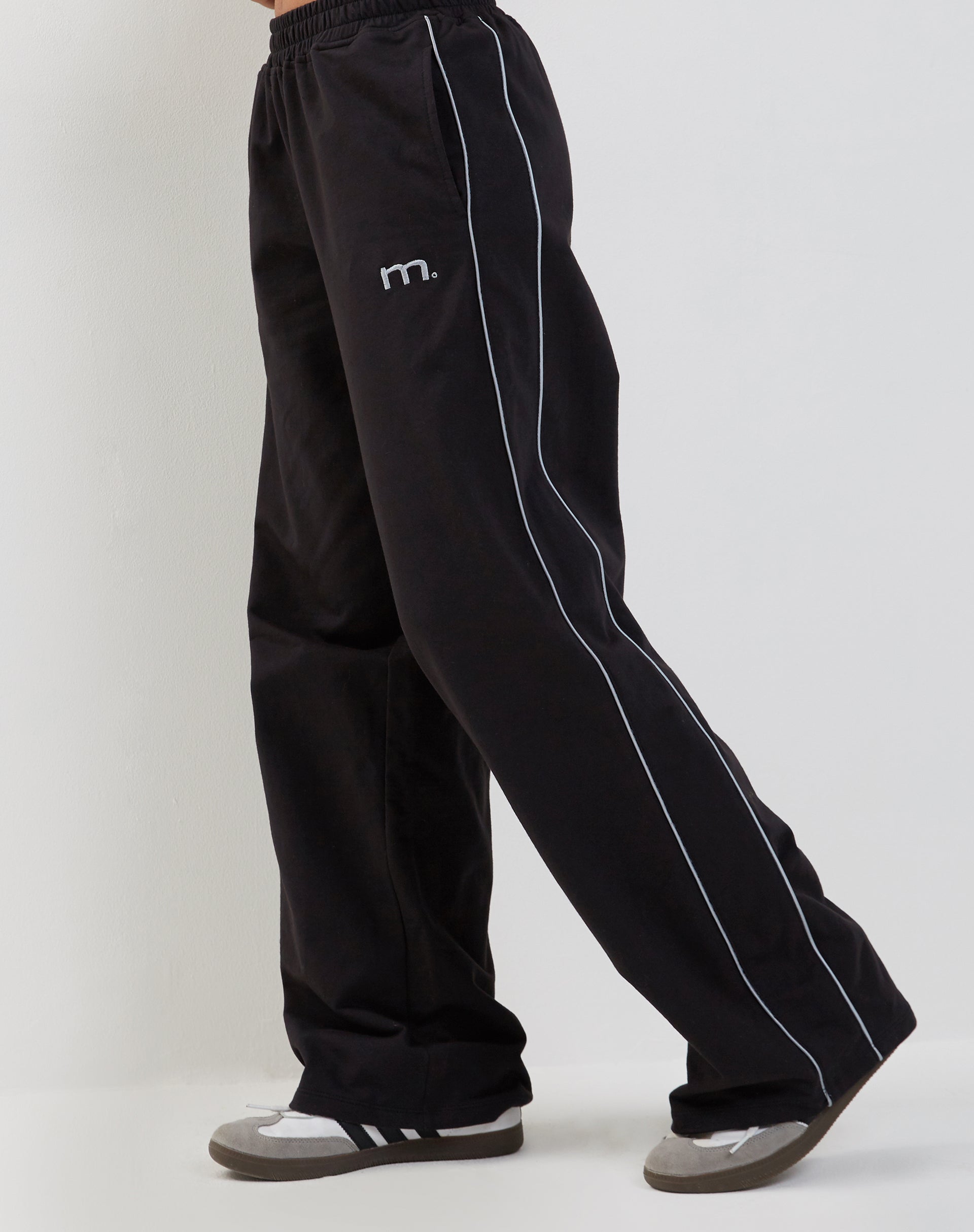 Imagen de Benton Wide Leg Jogger en negro con ribete gris oscuro y bordado "M